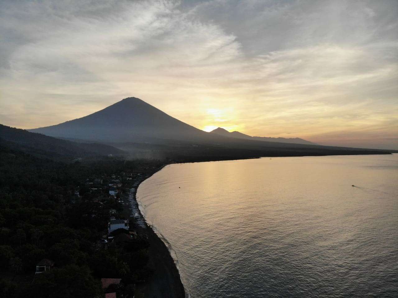 Aerial view of the Amed coastline at dusk with Mount Agung on the horizon